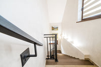 Indoor staircase with a black steel handrail attached to the wall and a matching railing