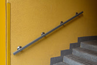 Indoor staircase with a modern metal handrail mounted on a yellow wall